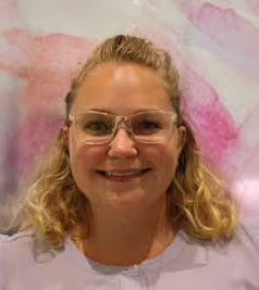 The image shows a woman with glasses wearing a light purple top smiling at the camera.
