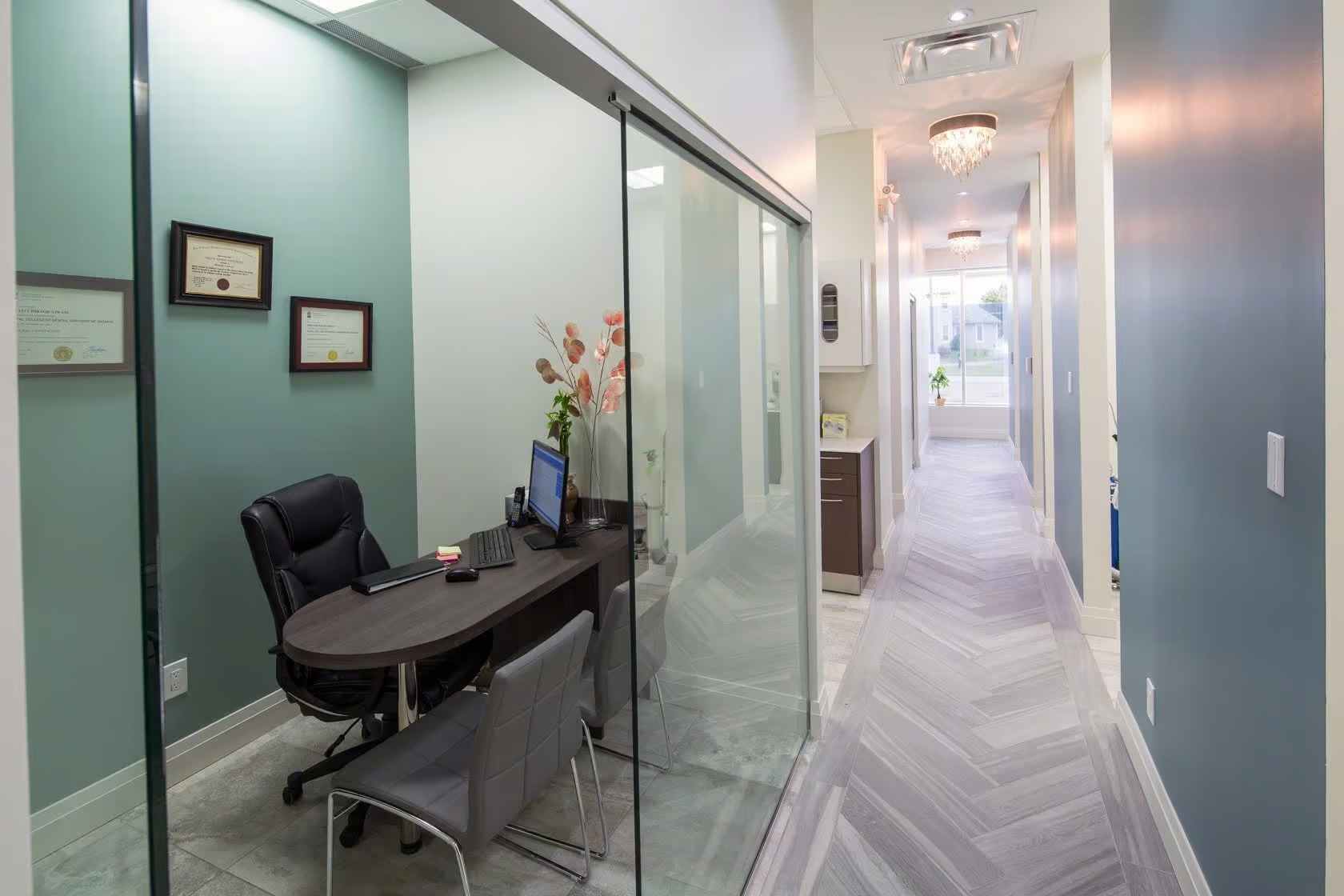 The image shows an interior view of an office hallway with glass partitions, a wooden floor, and a modern decor style.