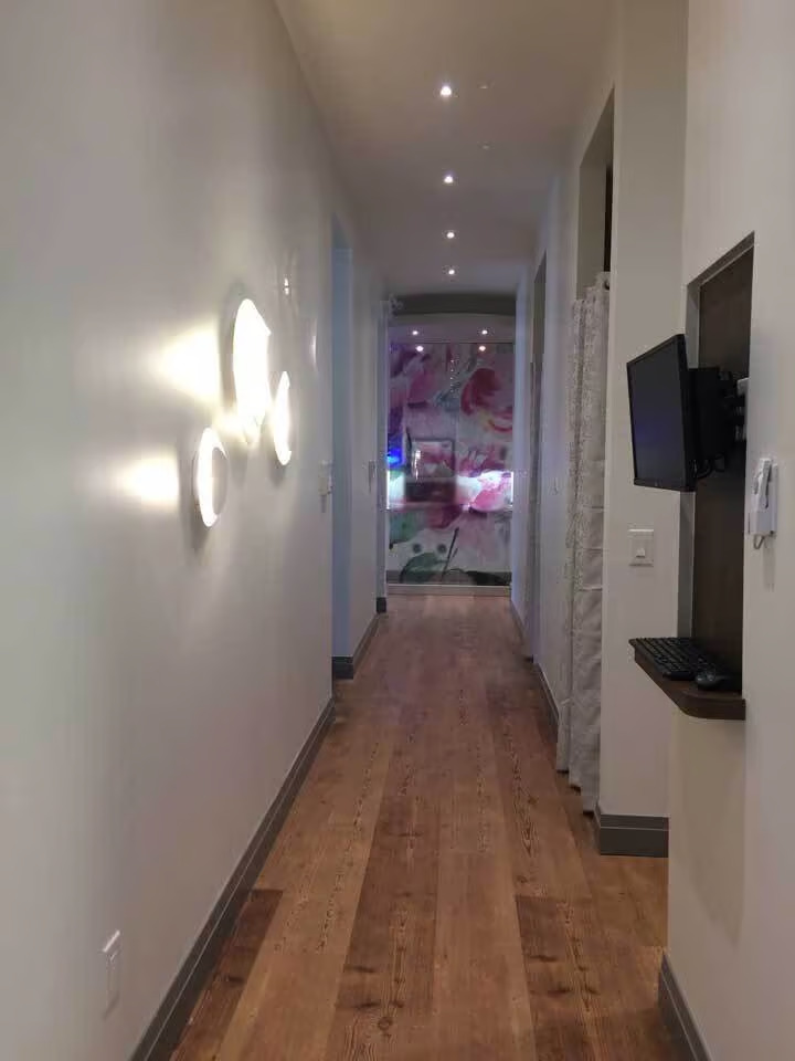 The image shows an interior hallway with a patterned wallpaper, a light fixture, and a television mounted on the wall.