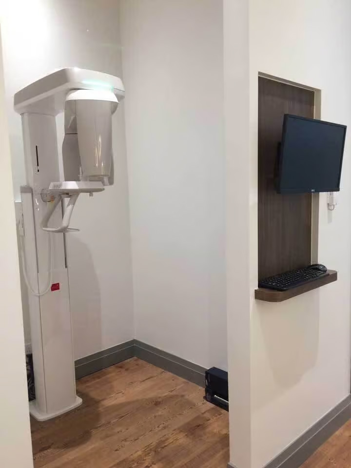 An image capturing a small room with a dental machine on the left side and a television monitor on the right wall.