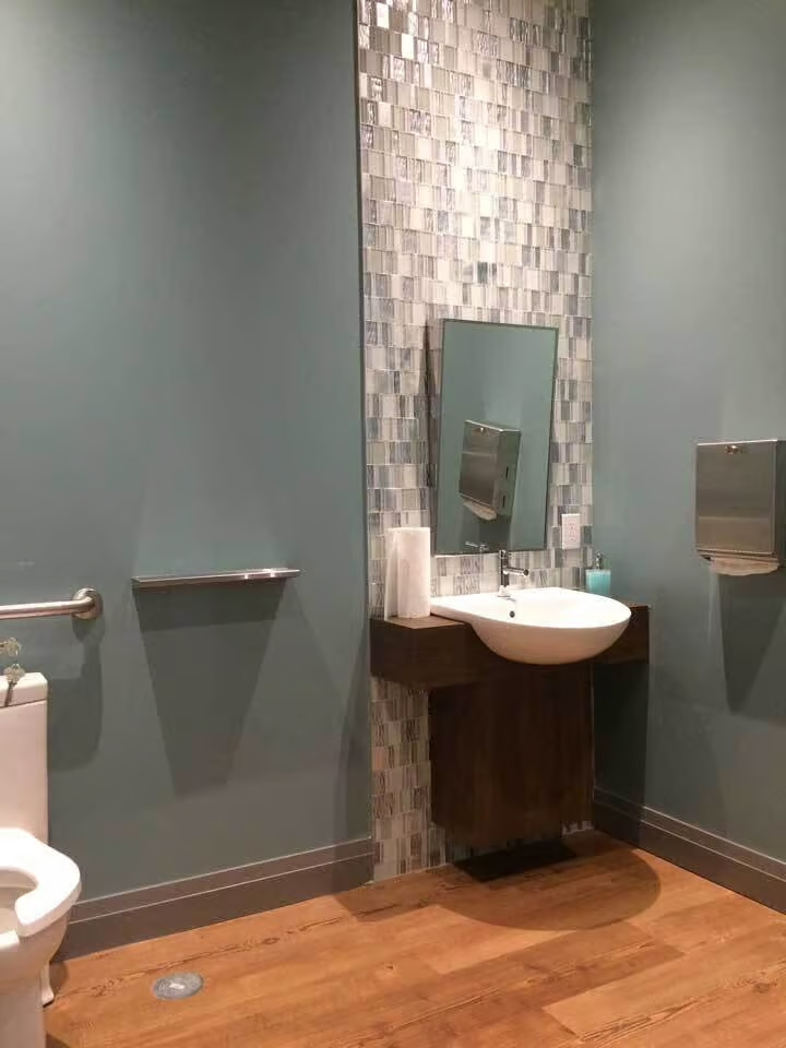 A clean and well-maintained bathroom with a modern design featuring a wall-mounted sink, mirror, and decorative tile accent.
